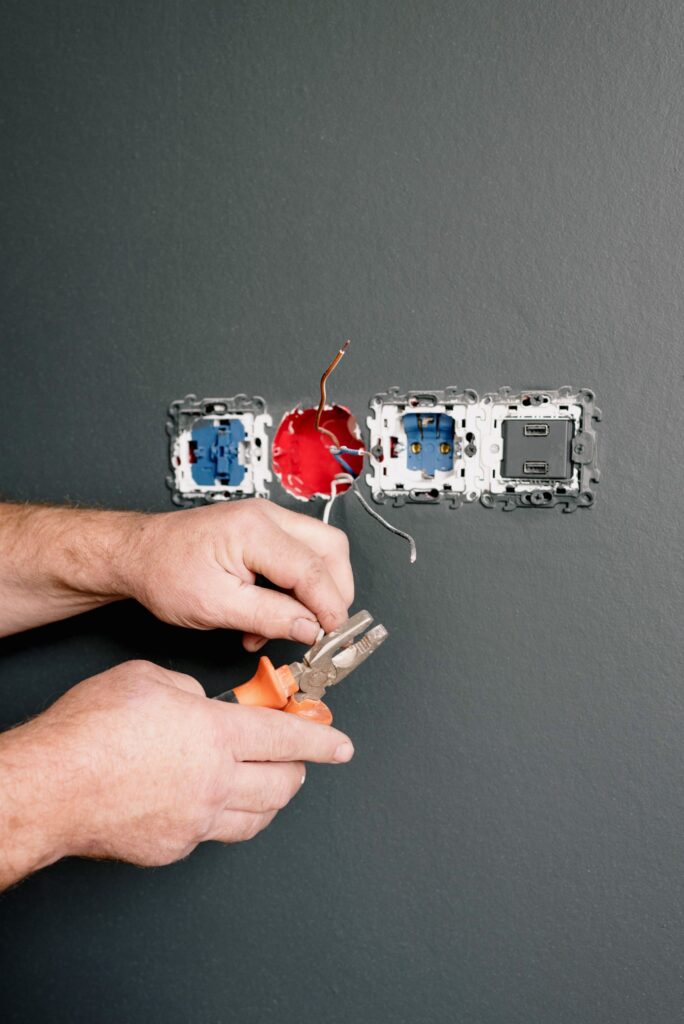 An electrician re-wires a wall socket | Kendra Electrical